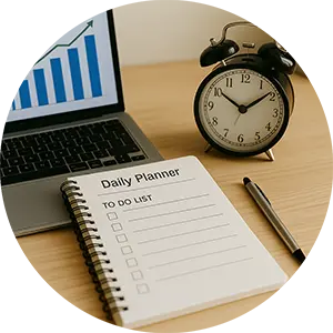 Productivity tools on a desk – daily planner, clock, laptop